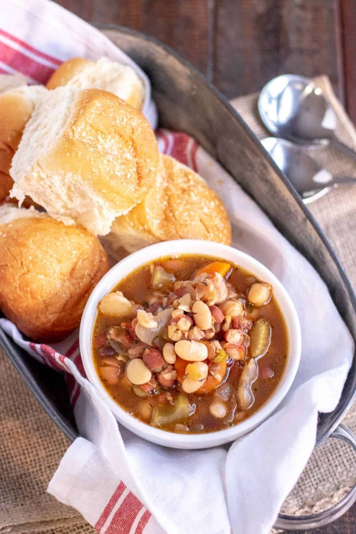 15 bean soup in a white bowl with rolls