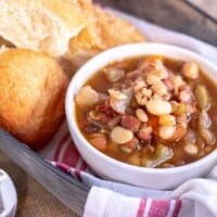 15 bean soup in a white bowl with rolls