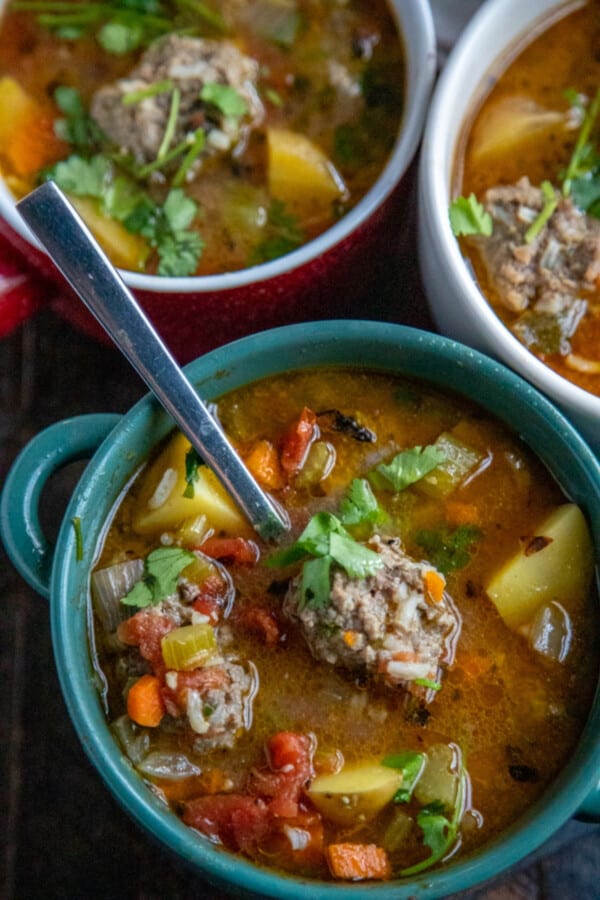 albondigas in teal bowls with a spoon