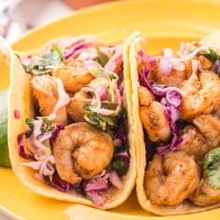 Baja shrimp tacos on a yellow plate.