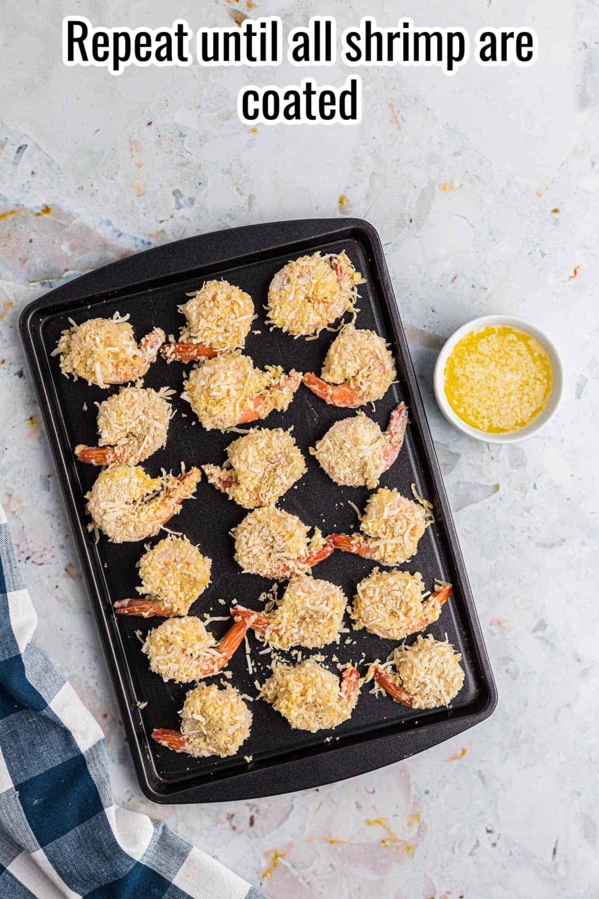 breaded shrimp with a bowl of melted  butter drizzled over the top on a sheet pan.