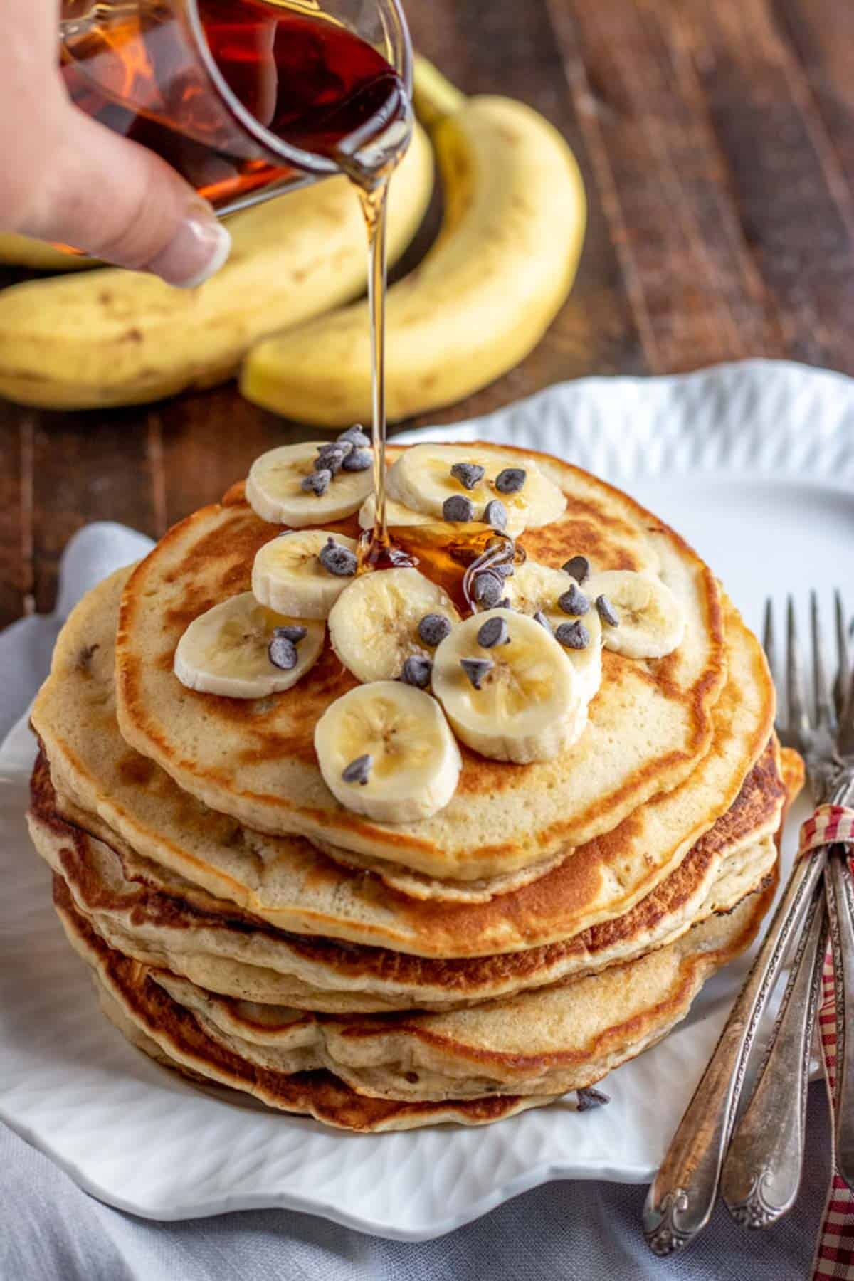 banana pancakes with syrup being poured over