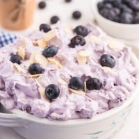 blueberry fluff salad in a white bowl with a blue gingham napkin.