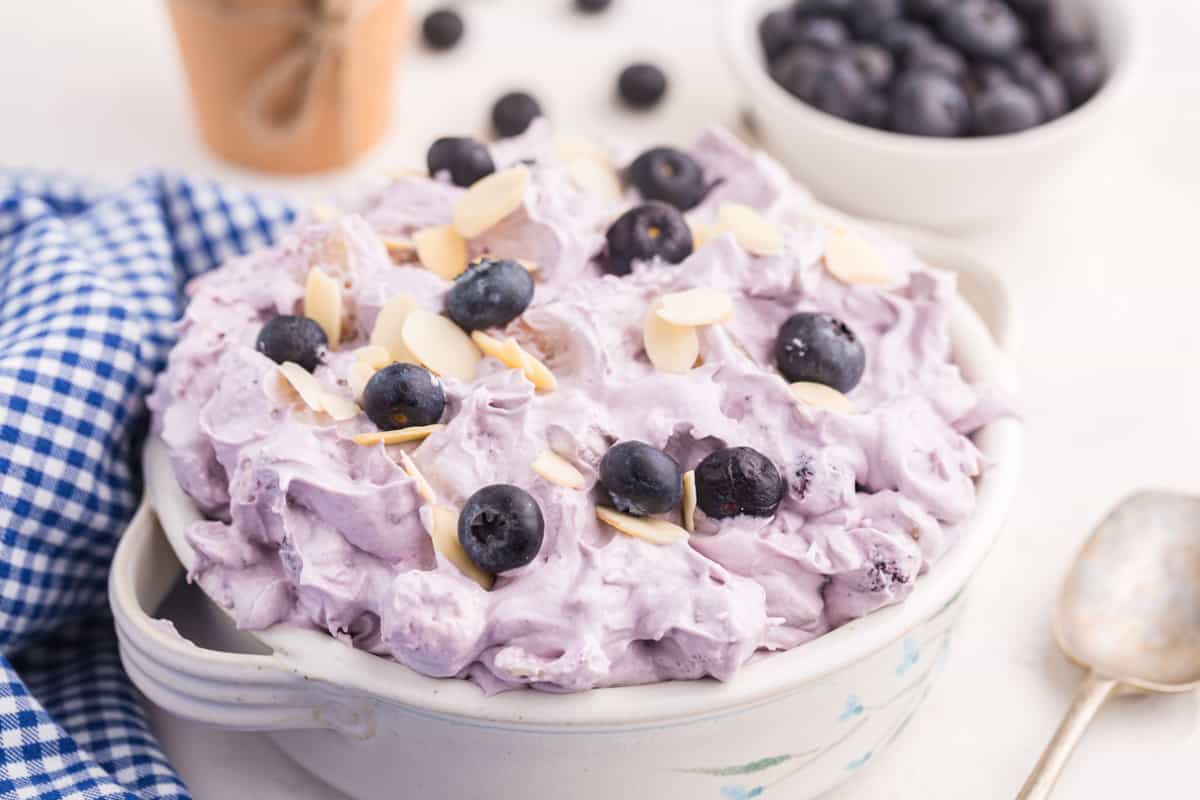 blueberry fluff salad in a white bowl with a blue gingham napkin.