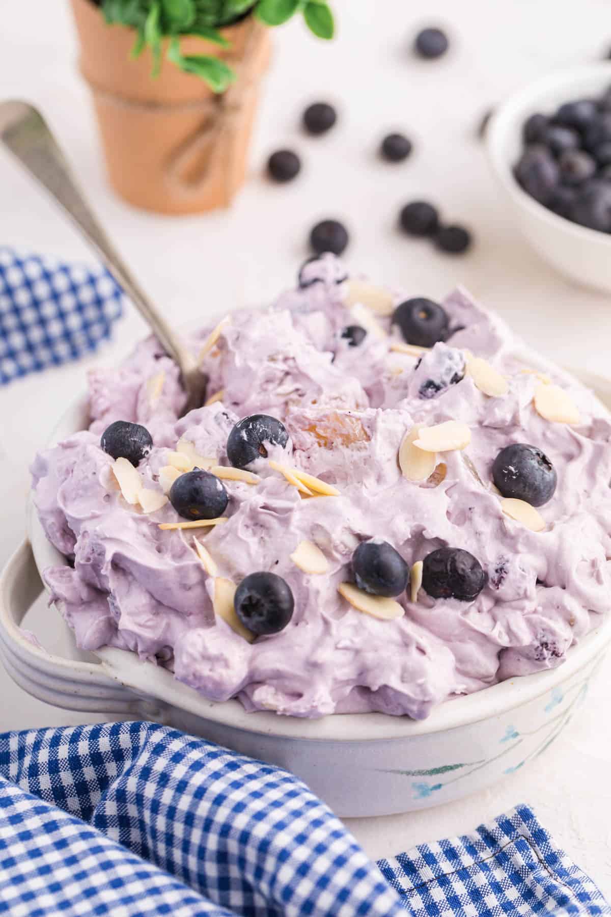 blueberry fluff salad in a white bowl with a blue gingham napkin.