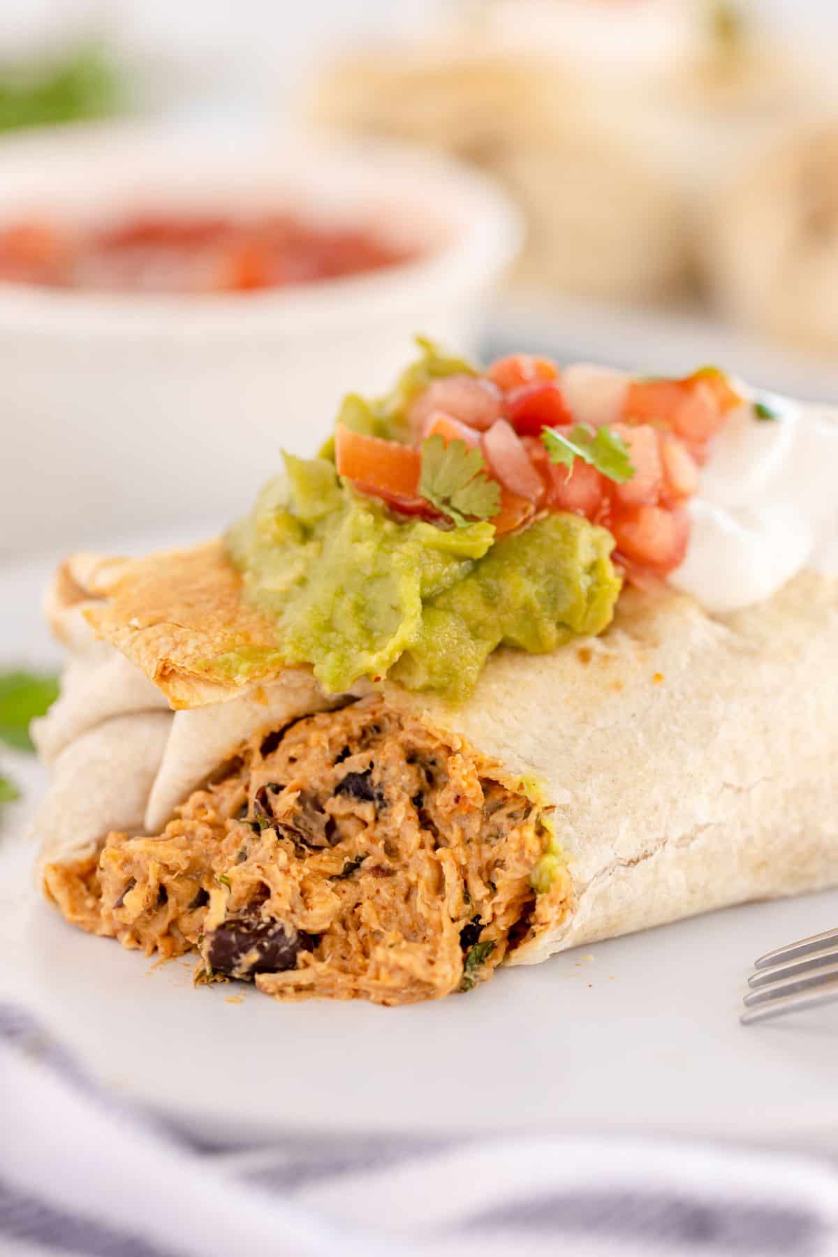 chicken chimichanga on a plate, cut open to show inside.