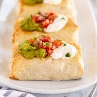 baked chimichangas on a white plate.