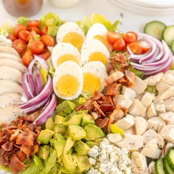 A plate of Cobb salad with chicken, bacon, and eggs.