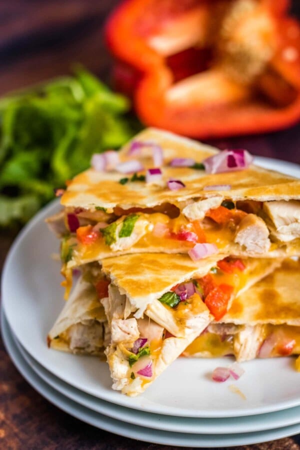 chicken quesadillas on a stack of white plates