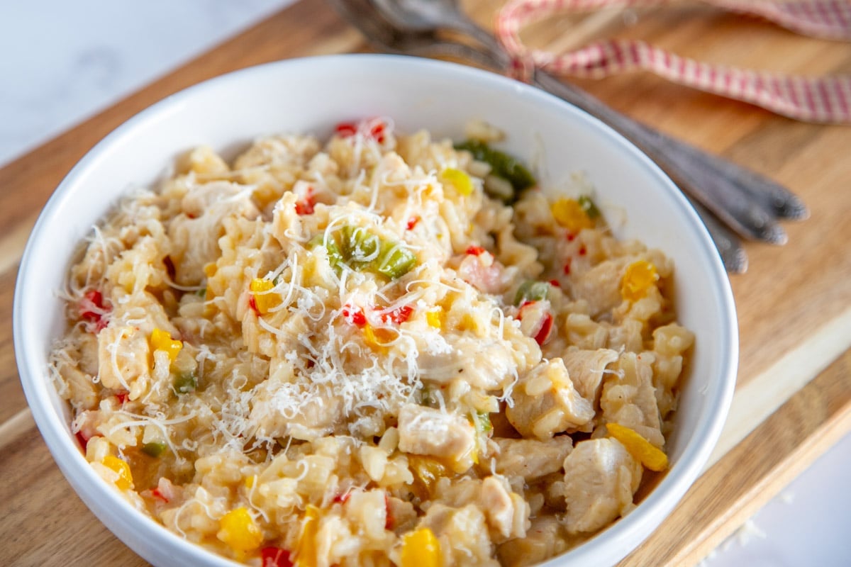 chicken risotto in a white bowl on a wooden chopping board