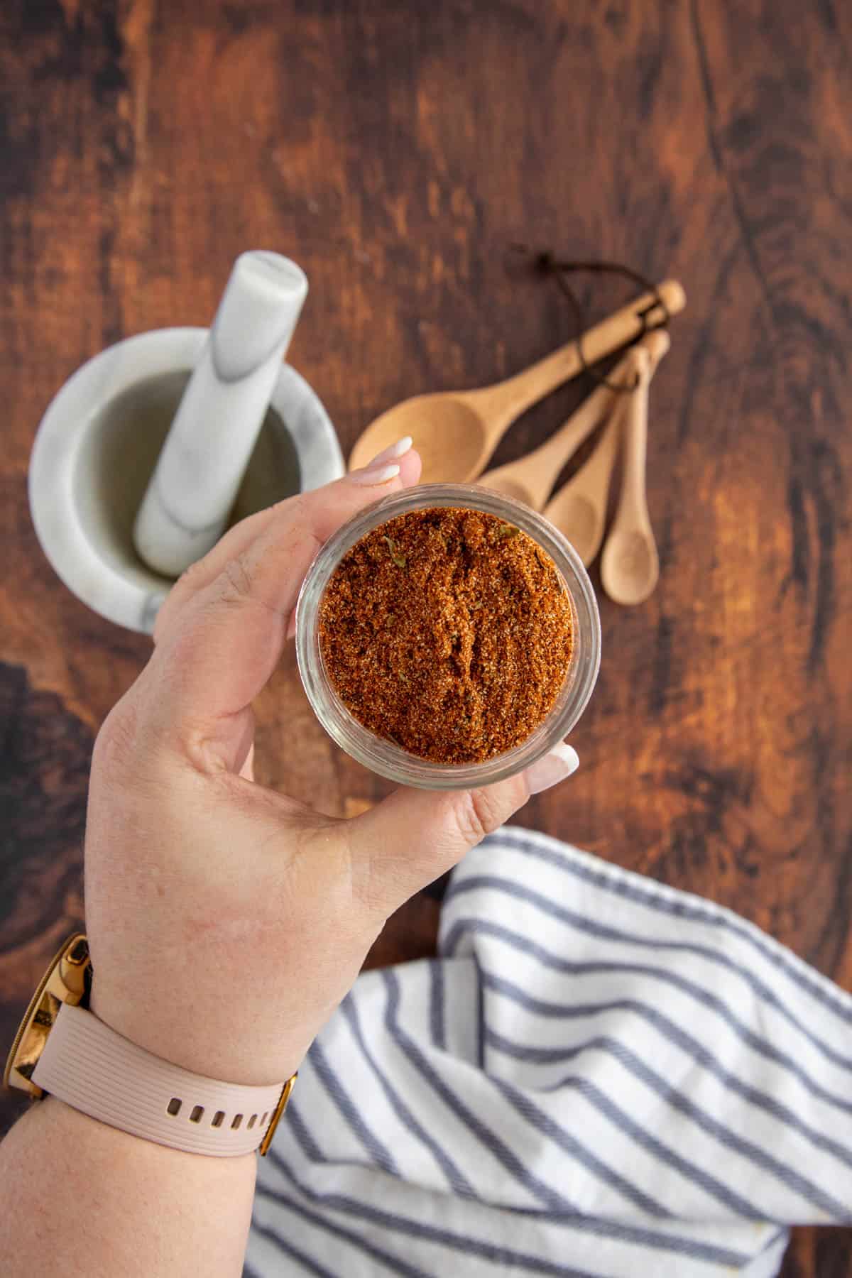 hand holding a jar of chili powder