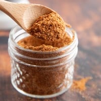 chili powder in a glass jar with a wooden spoon