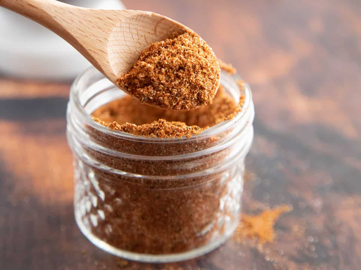 chili powder in a glass jar with a wooden spoon