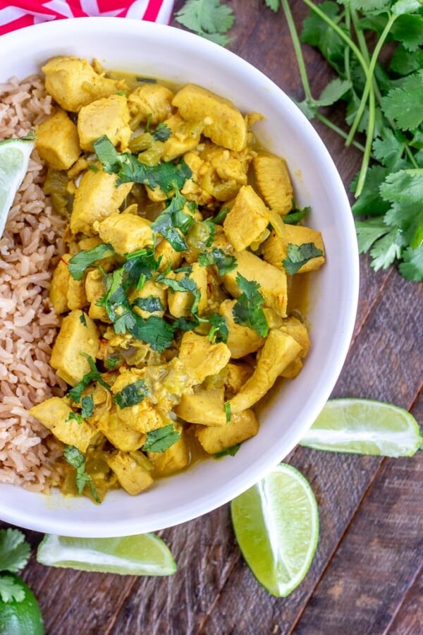 Coconut Chicken Curry - overhead shot, vertical, white bowl with limes and cilantro