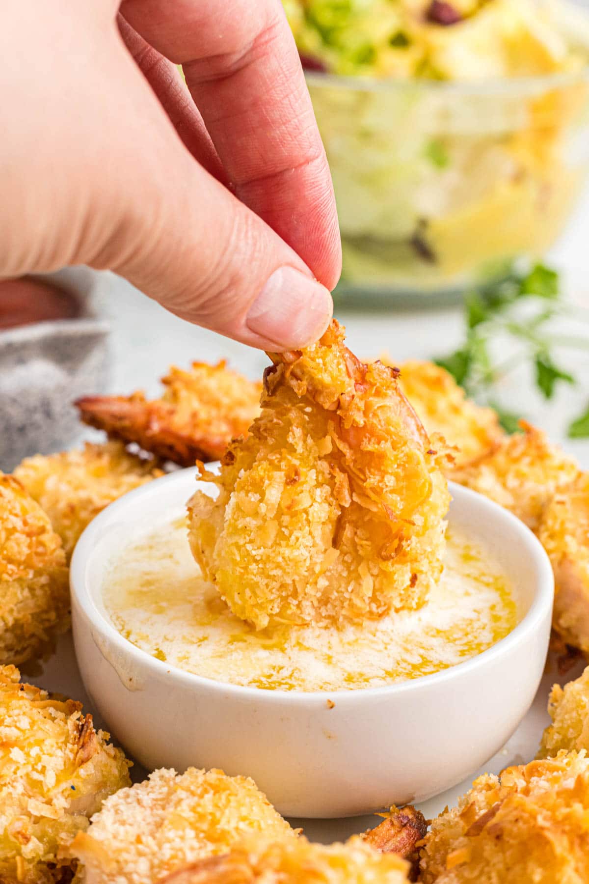 hand dipping shrimp into a sauce