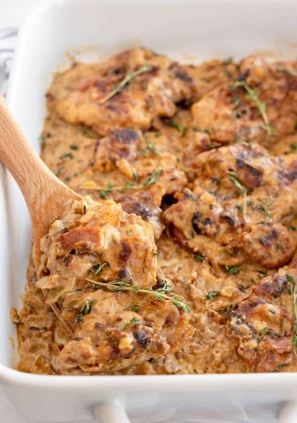 chicken casserole in a white dish with a wooden spoon.