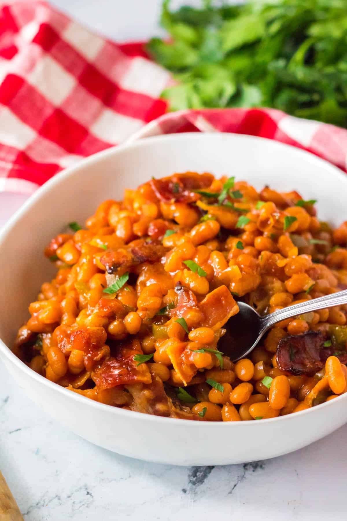 baked beans in a white bowl with red and white napkin.