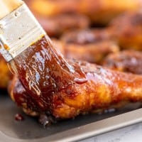 brushing bbq sauce onto chicken.