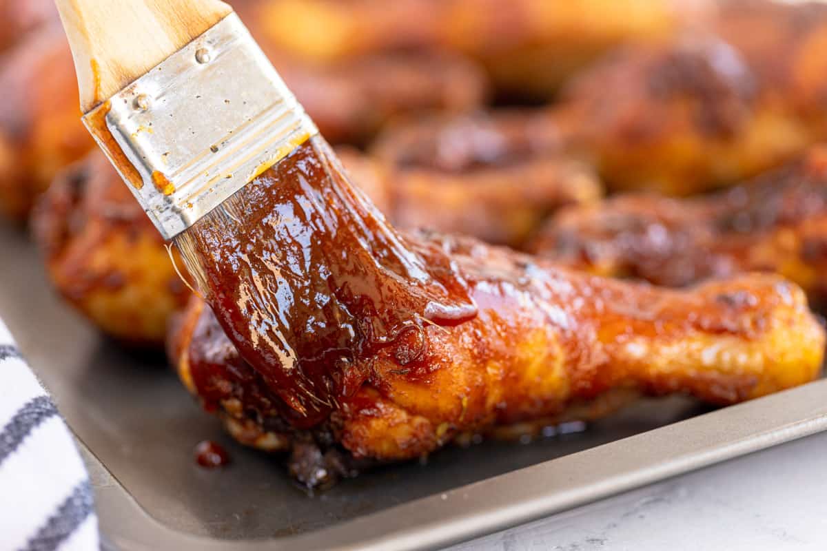 brushing bbq sauce onto chicken.