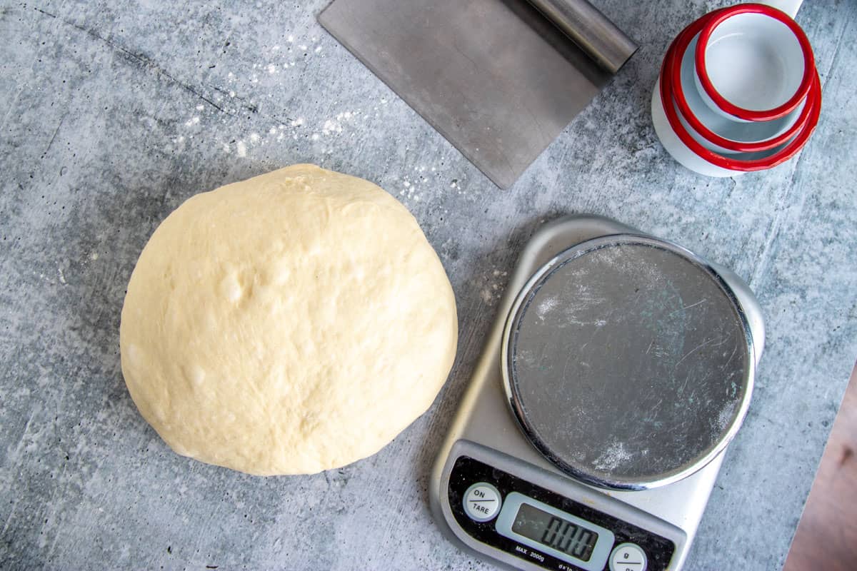 ball of hamburger bun dough with a kitchen scale.