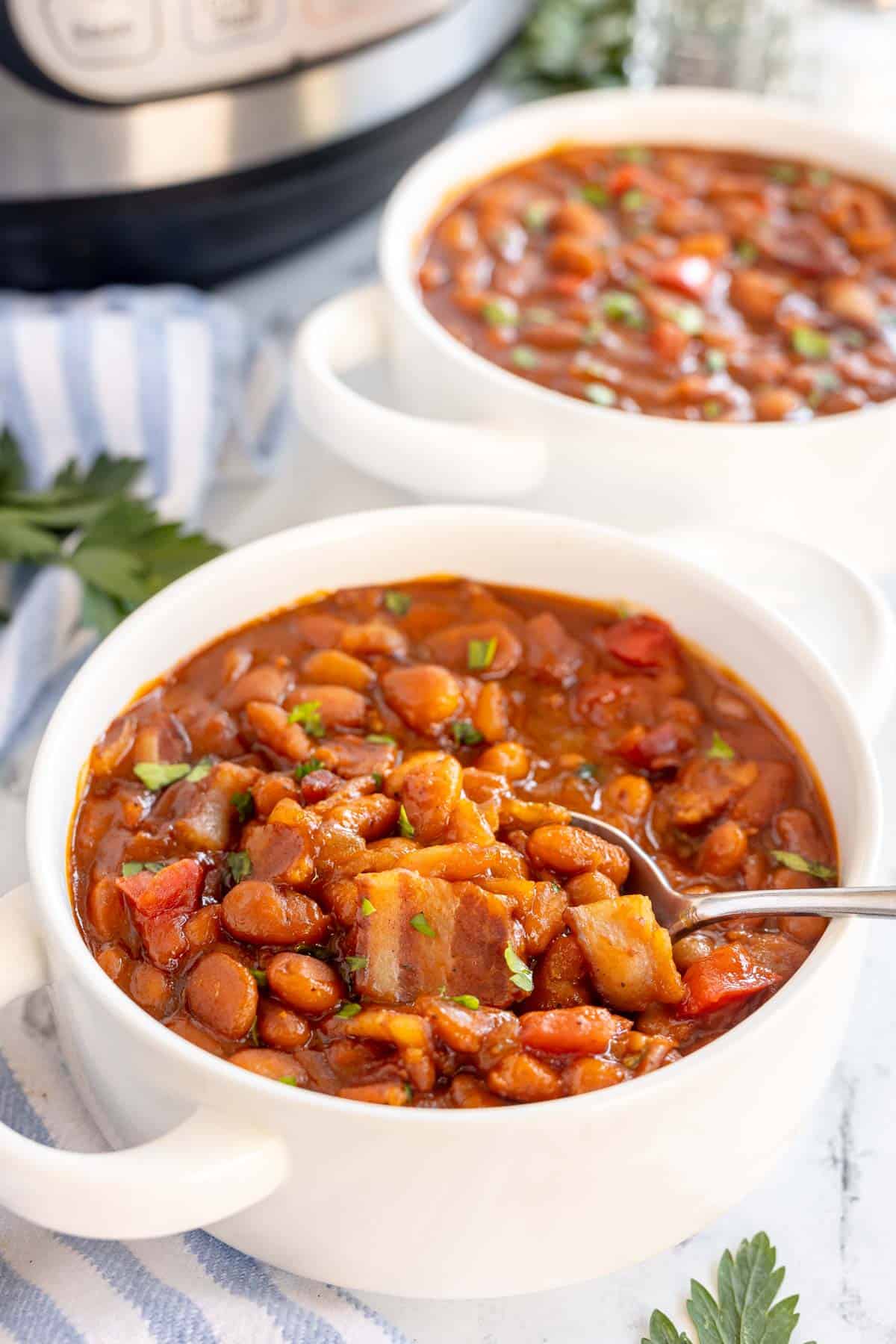 baked beans in a white bowl with a spoon.