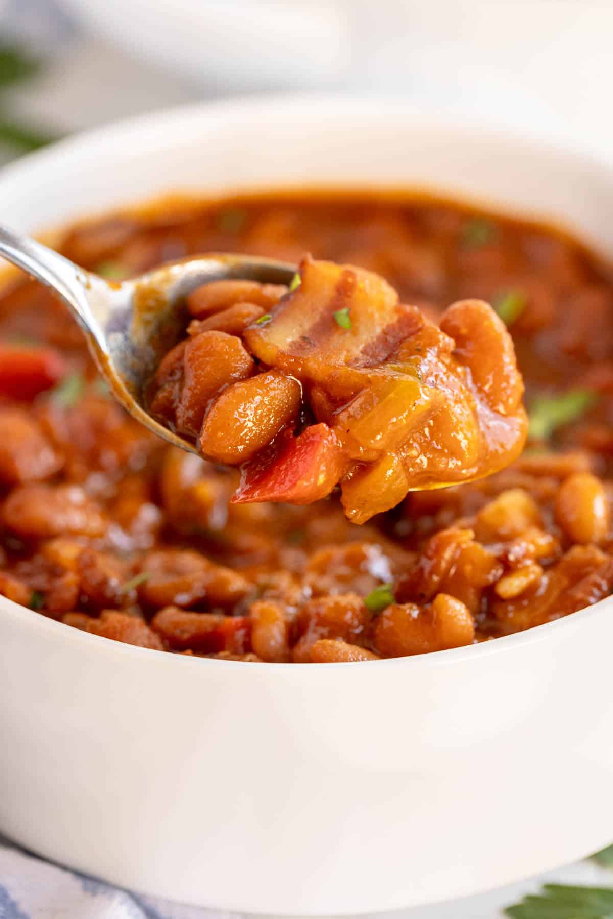 baked beans in a white bowl with a spoon.