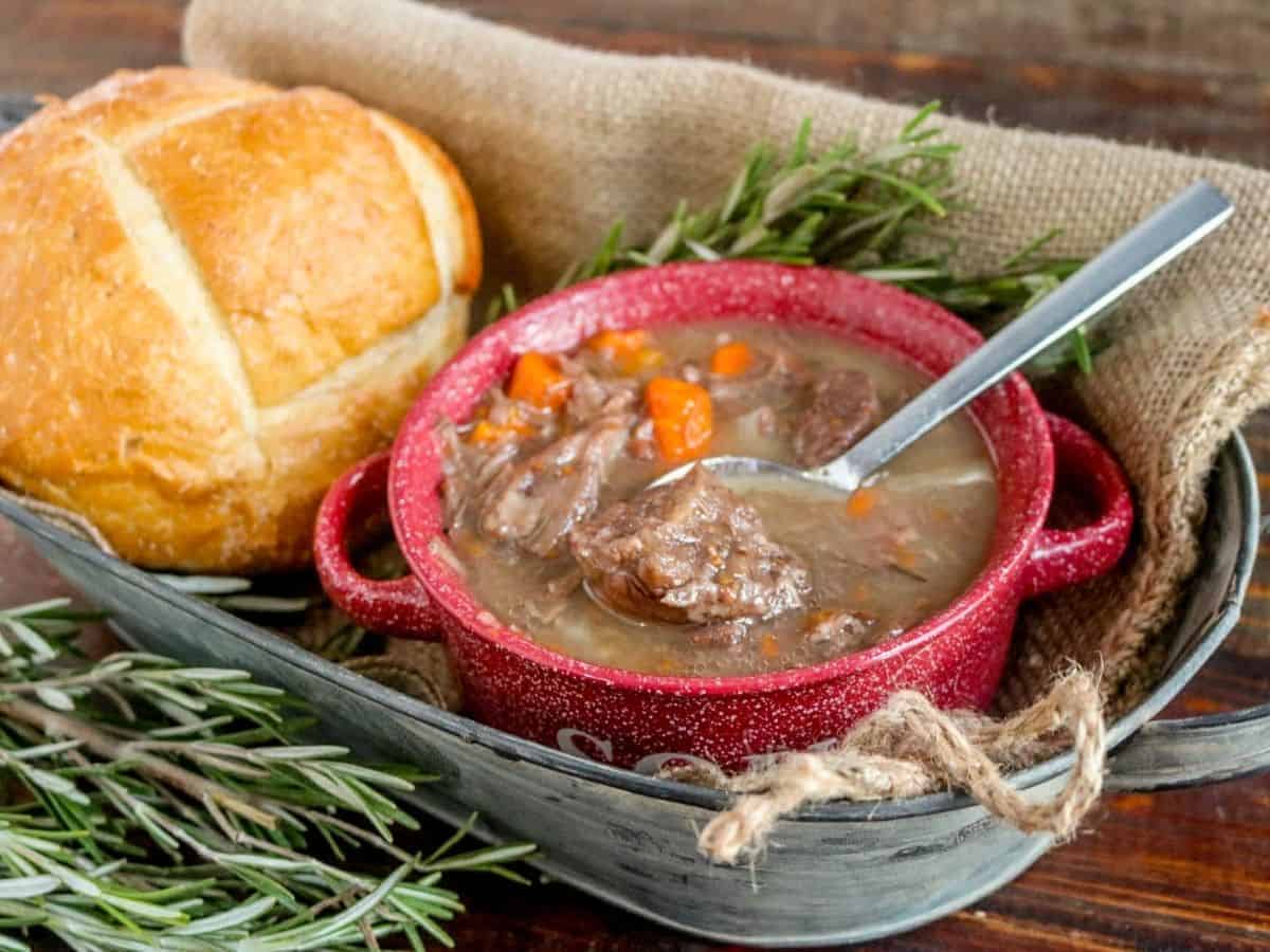 Beef stew in a red bowl with bread