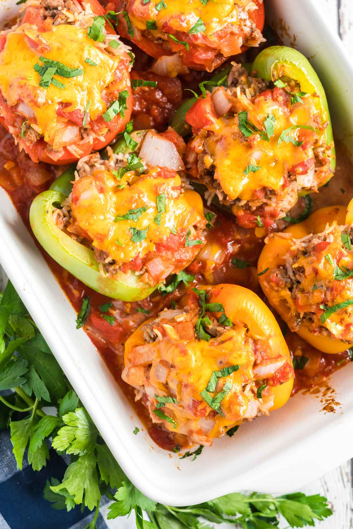 stuffed peppers in a white baking dish with parsley scattered