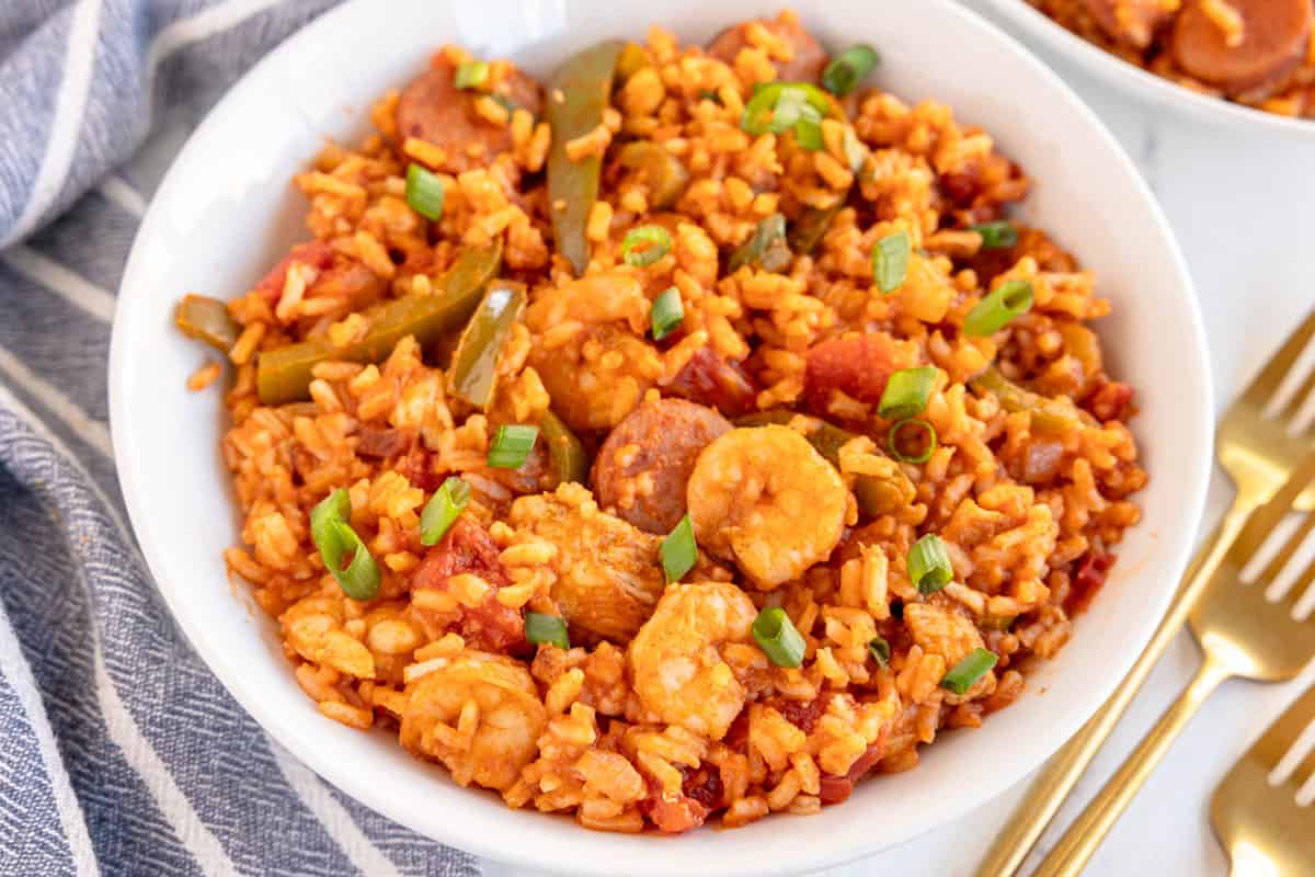 a bowl of jambalaya with a striped napkin.