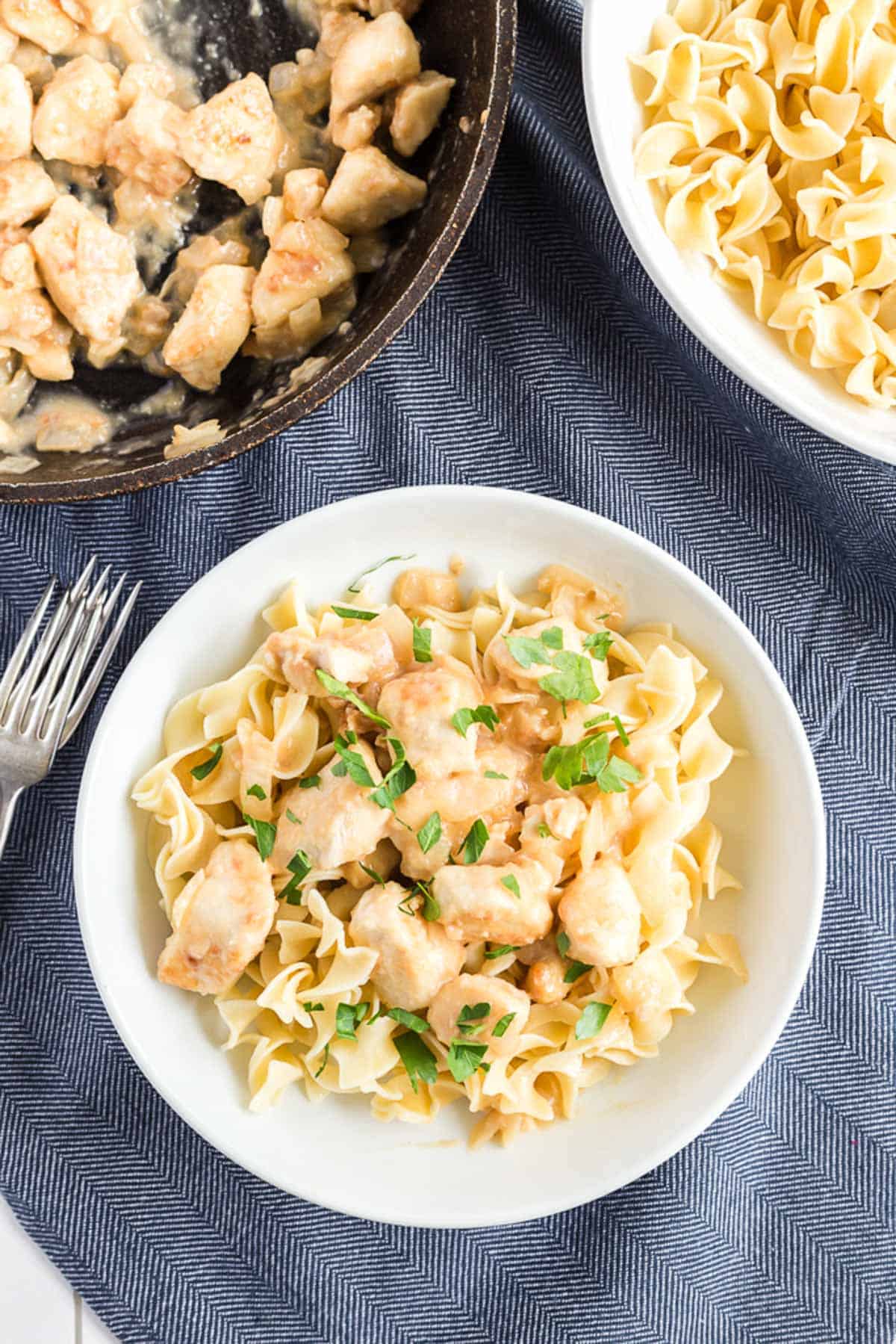 lemon chicken in a white bowl, with a skillet and fork in teh back group