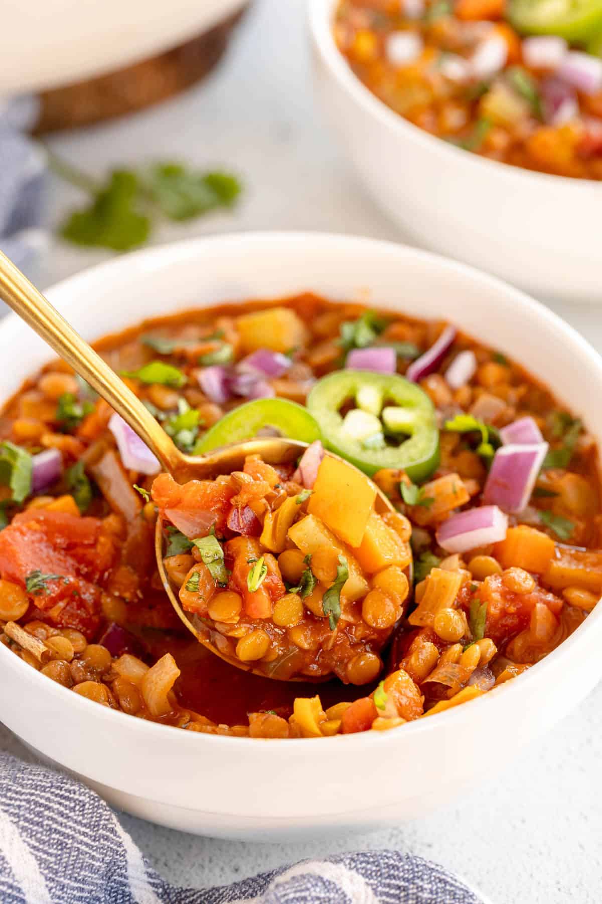 lentil chili in a white bowl with a spoon.