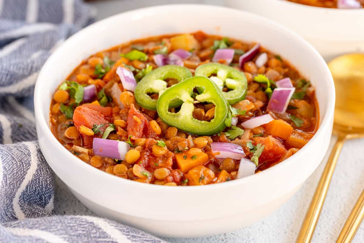 lentil chili in a white bowl with a blue napkin.