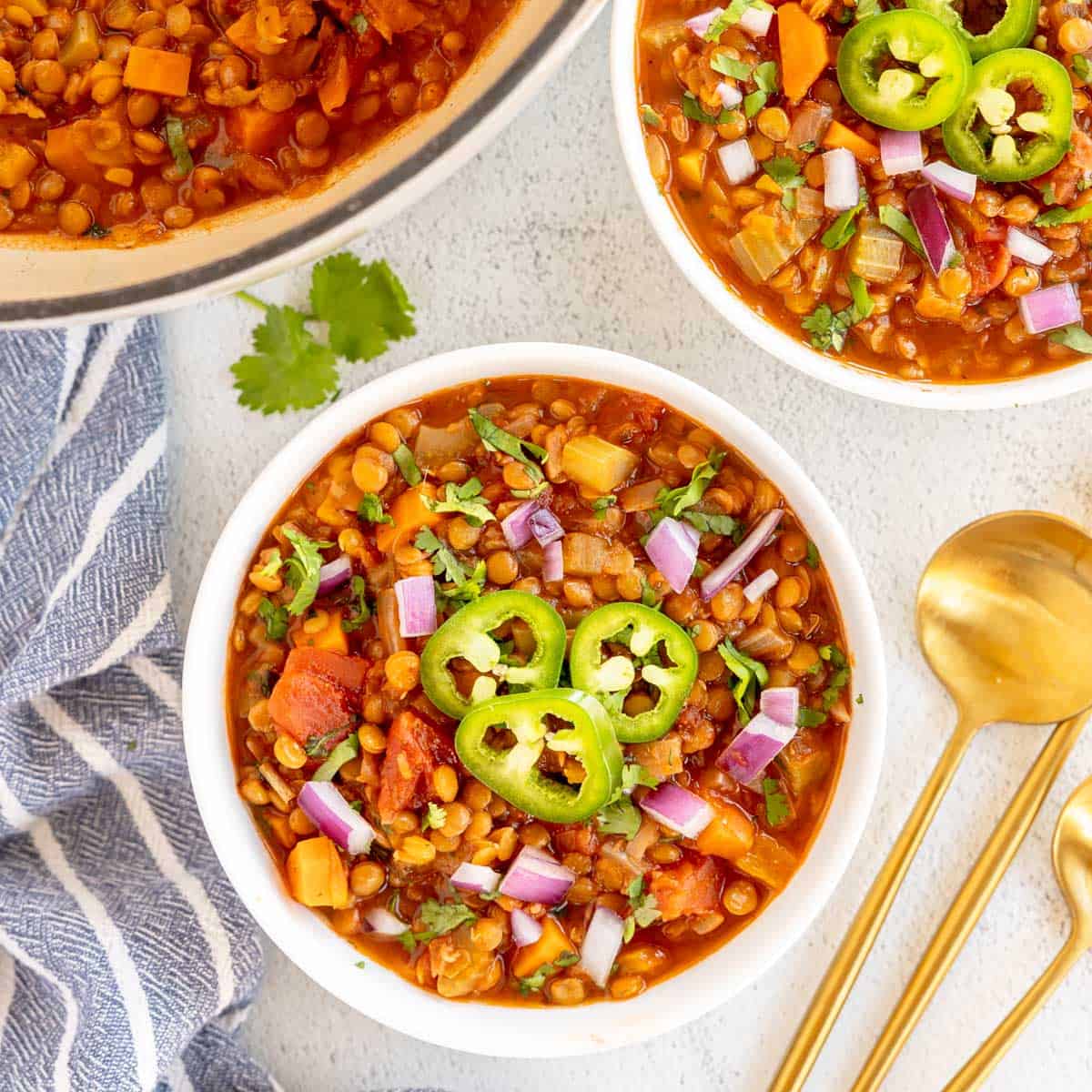 lentil chili in a white bowl with a blue napkin.