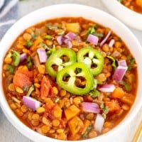 lentil chili in a white bowl with a blue napkin.