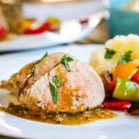 a dinner plate with pork tenderloin and vegetables