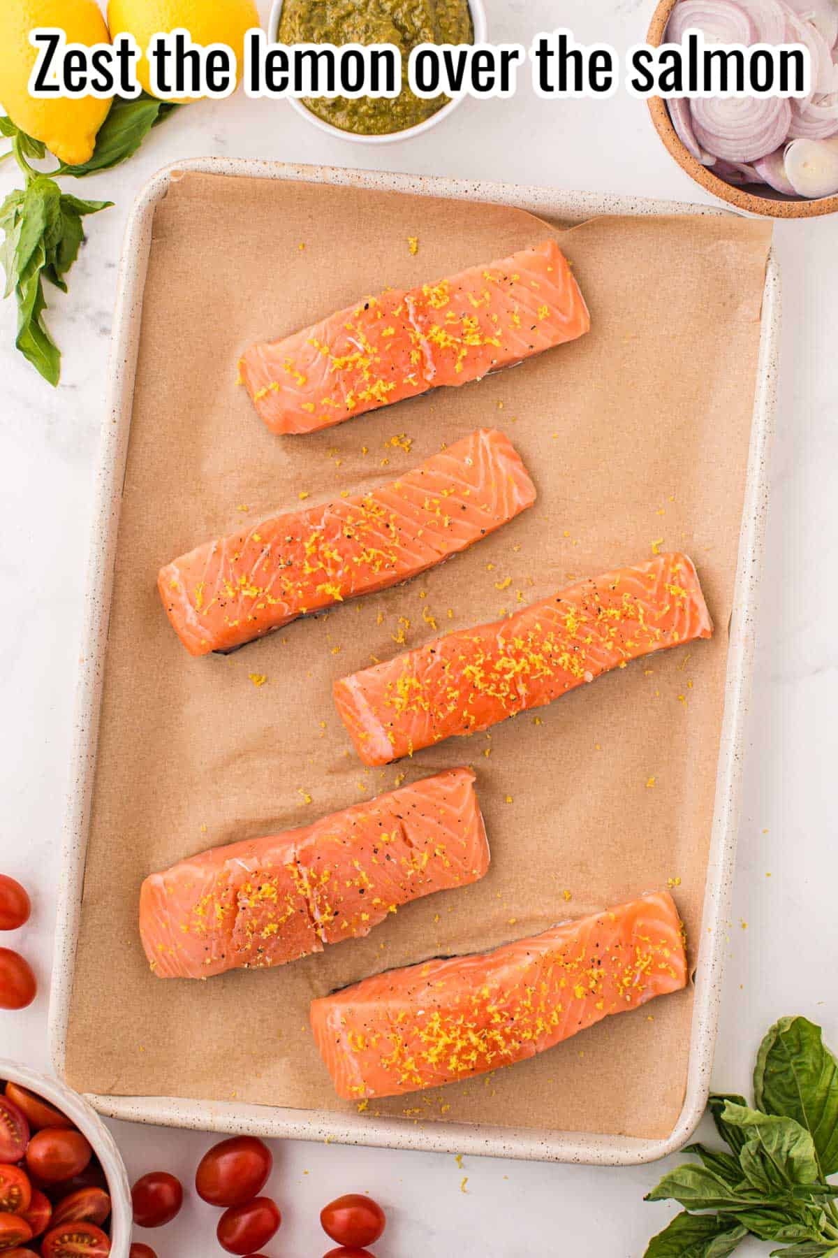 lemon zest over salmon fillets on a sheet pan.