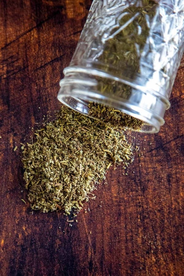 homemade poultry seasoning on a wooden board with a glass jar