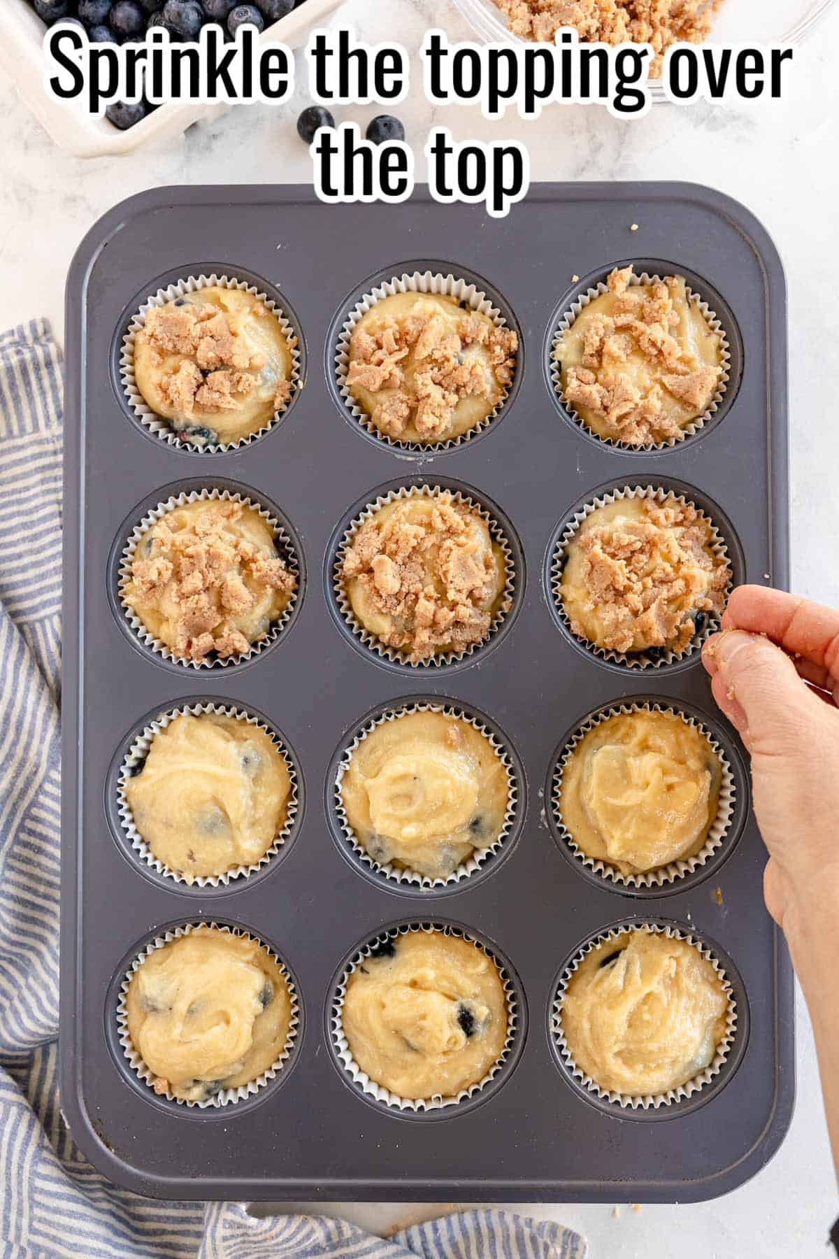 a muffin tin with 12 muffins, and a hand adding topping.