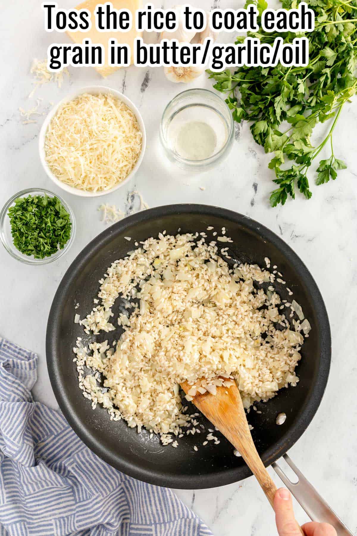 a black skillet with rice being stirred with a wooden spoon.