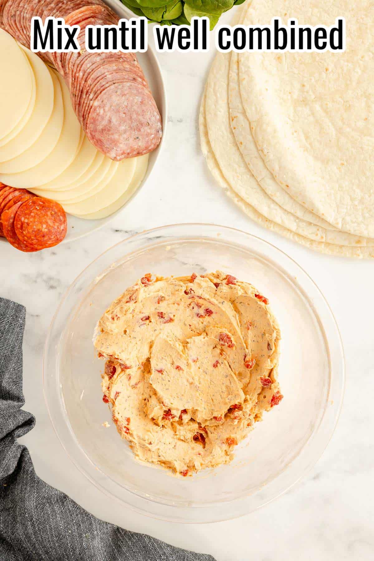 A bowl of mixed cream cheese, seasonings, cheese and roasted red peppers.