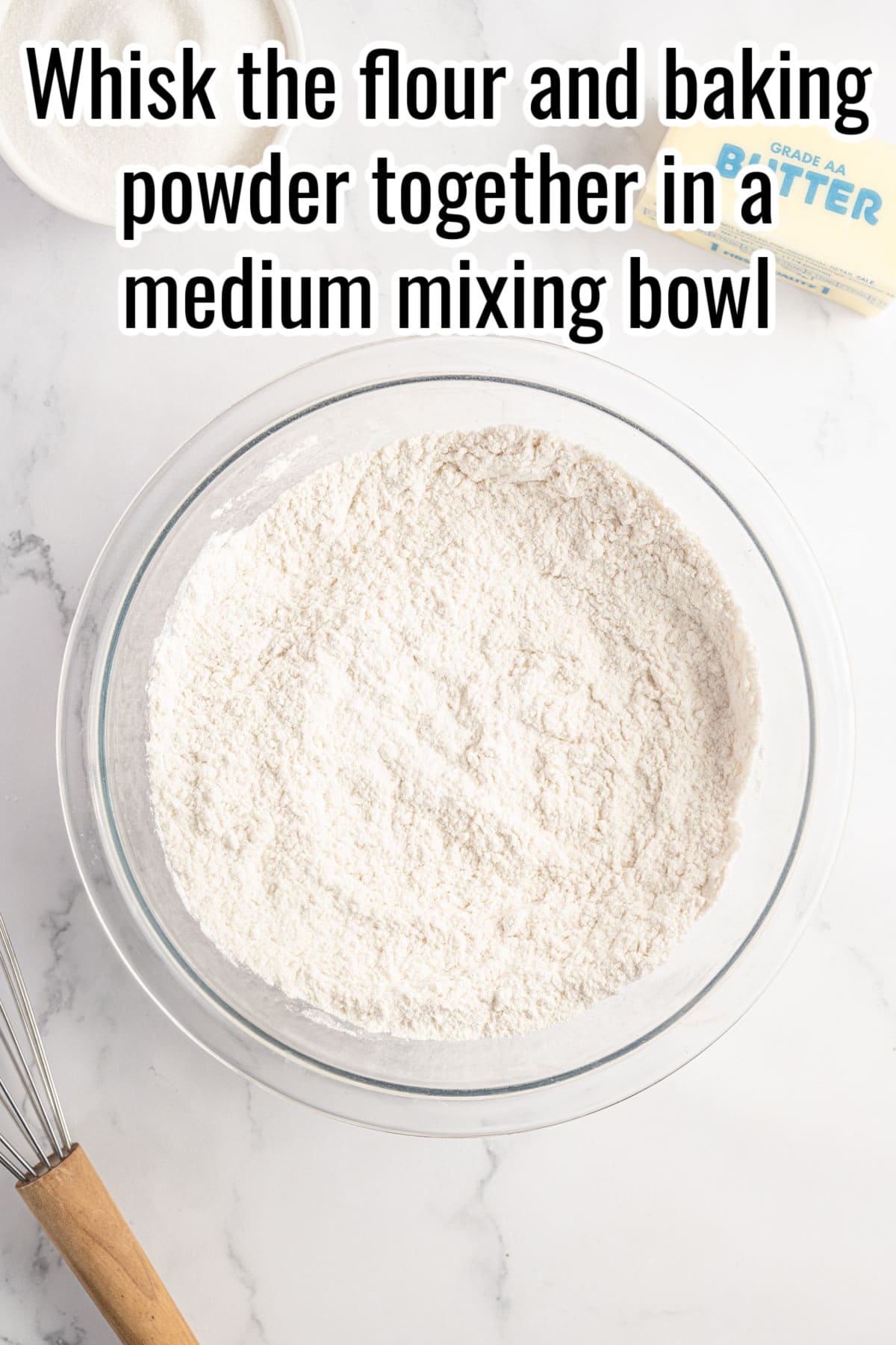 a glass bowl with flour and baking powder in it.