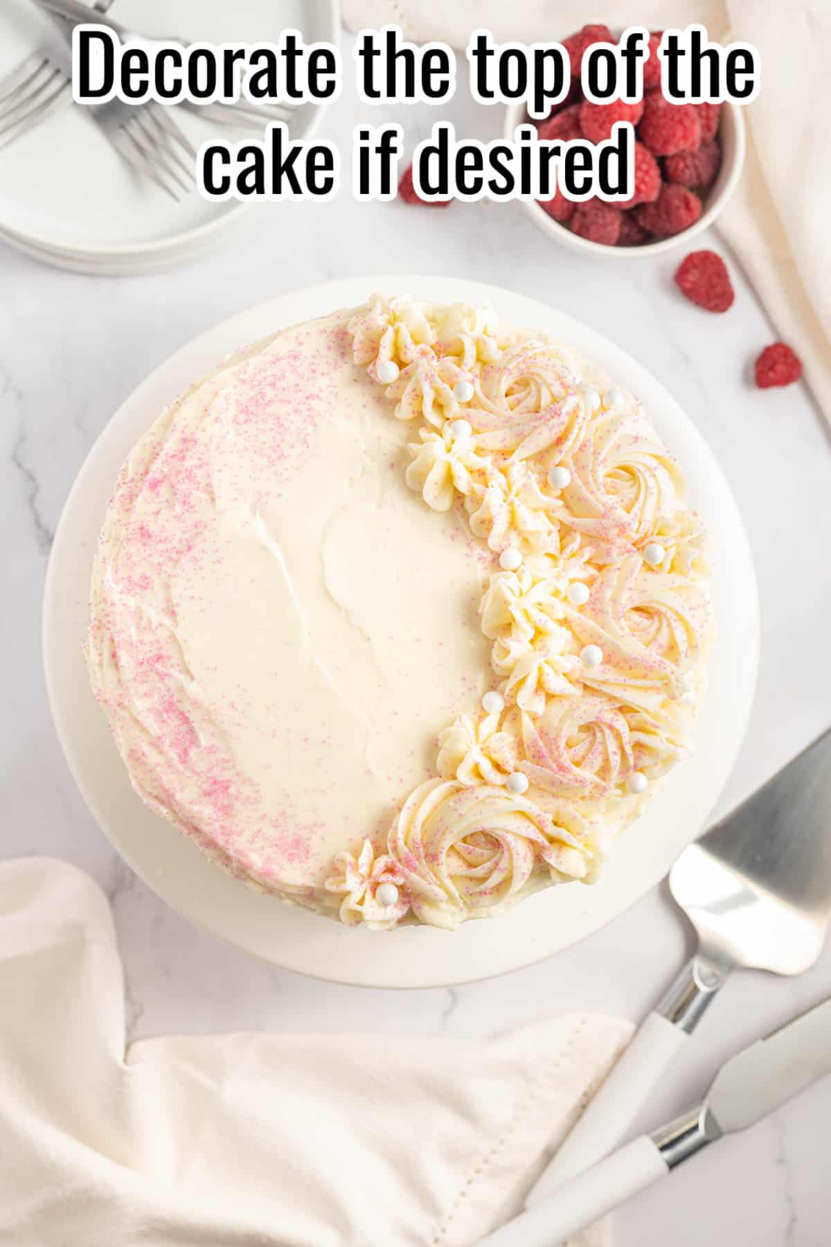 A white cake with piped flowers, and pink sprinkles.