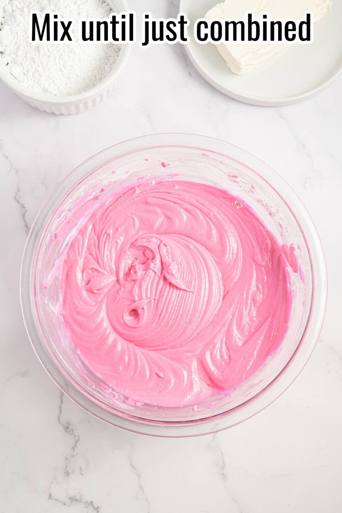 A glass bowl of pink cake batter.