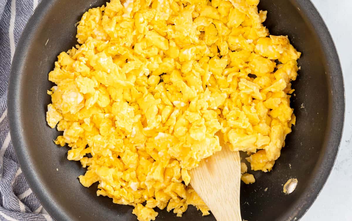 skillet with scrambled eggs and a wooden spoon.