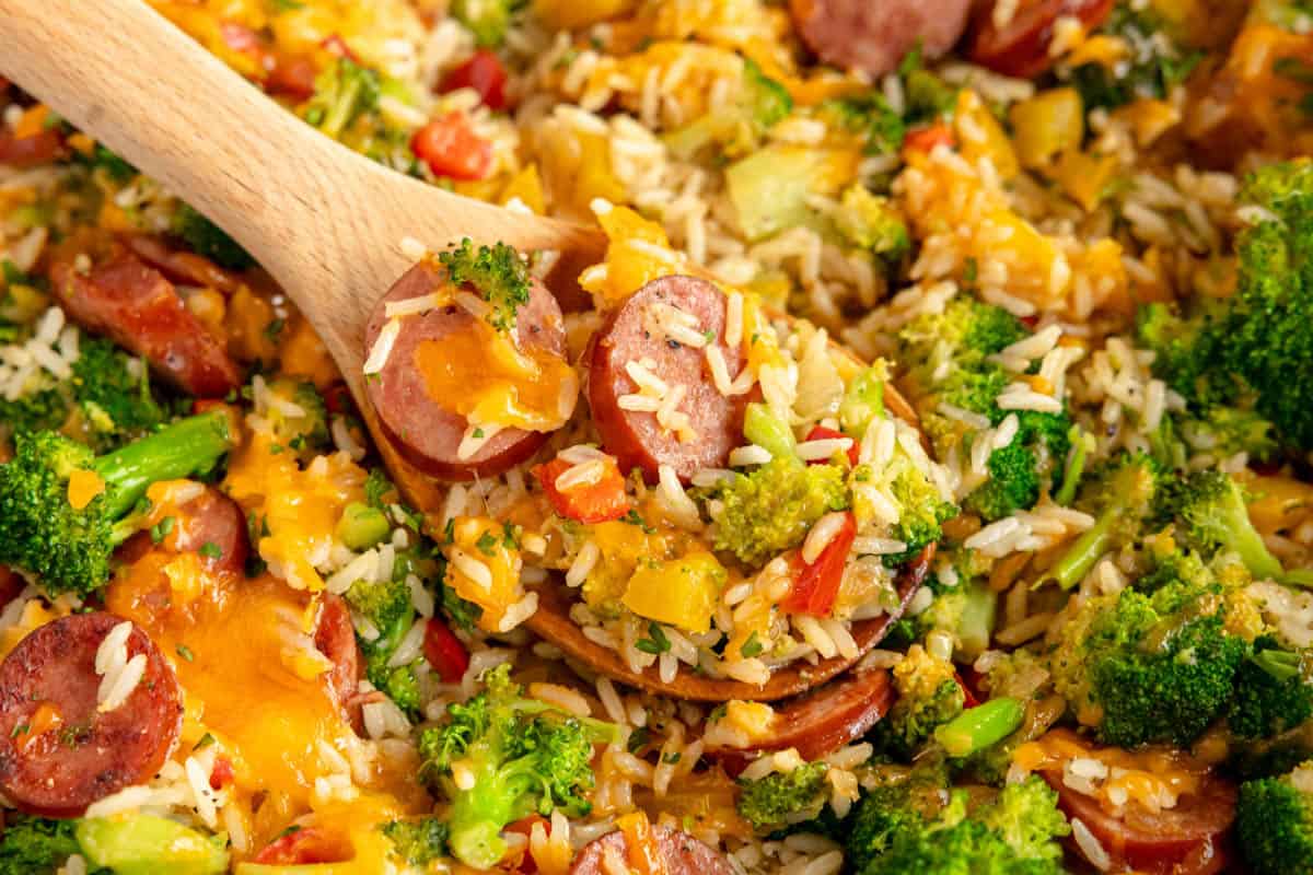 sausage and rice with vegetables on a wooden spoon.