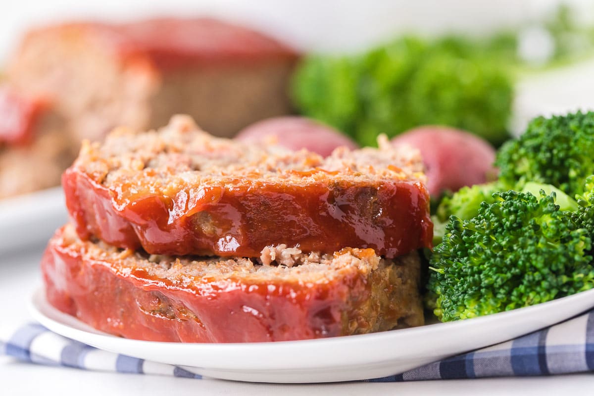 slices of meatloaf on a plate with steamed broccoli