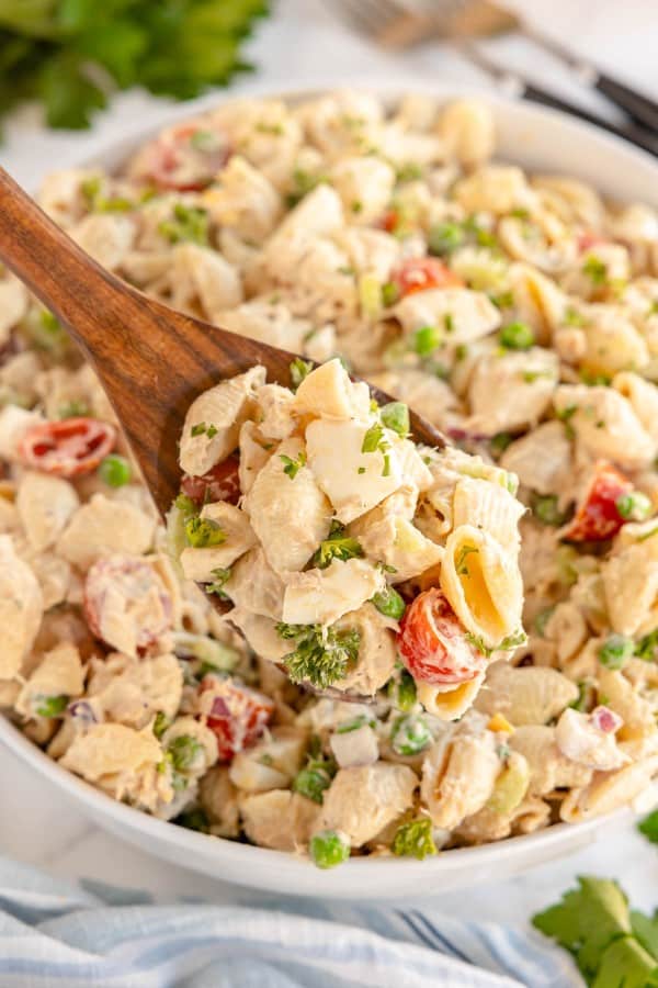 tuna pasta salad in a white bowl with a salad spoon.